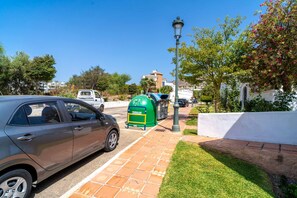 A parking area with a car, a green trash bin, and a lamp post. - Oasis de Capistrano Rabat 27 by Casasol (Nerja)