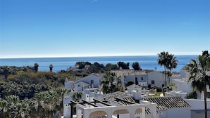 A coastal town with white buildings, palm trees, and a clear blue sky. - Oasis de Capistrano Rabat 27 by Casasol (Nerja)