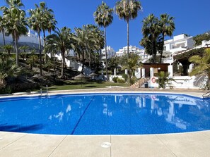 Una piscina azul cristalina rodeada de palmeras y edificios blancos.