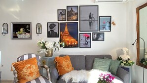 A living room with a sofa, armchairs, and a coffee table. There are wall-mounted pictures and a small table with a vase of flowers. - Oasis de Capistrano Rabat 27 by Casasol (Nerja)