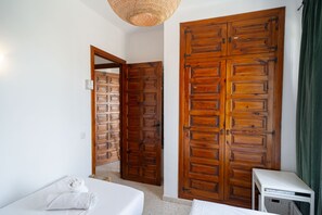 Une chambre comprenant un lit, un bureau et deux grandes armoires en bois.