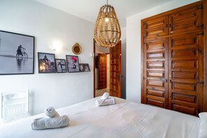 A hotel room with a bed, two towels, a wall-mounted mirror, and framed pictures. - Oasis de Capistrano Rabat 27 by Casasol (Nerja)