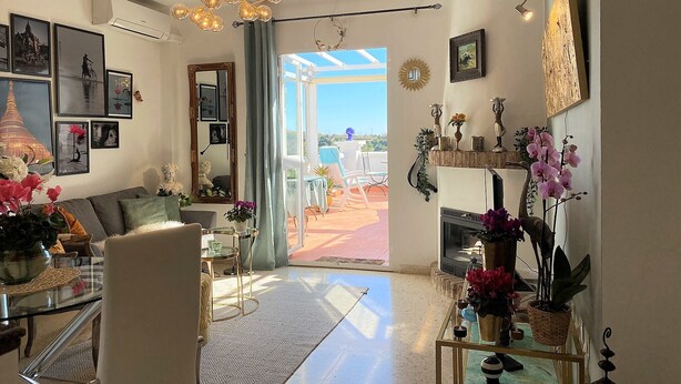A spacious living room with a large window, a chandelier, and various decorative items. - Oasis de Capistrano Rabat 27 by Casasol (Nerja)