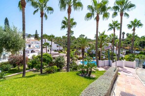 A resort with palm trees, a swimming pool, and a view of the surrounding buildings.
