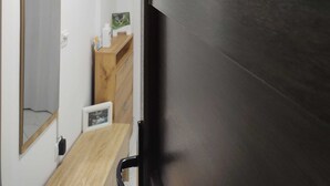 A room with a dark door, a wooden shelf with decorative items, a mirror, and a small wooden table. - Apartment Iskra (Plitvicka Jezera)