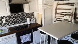 Cocina con salpicadero estampado, encimera blanca, estufa y comedor con taburetes.