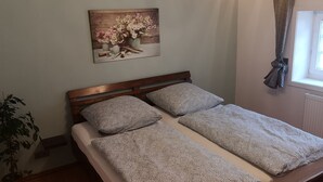 Una cama individual con cabecera de madera, dos almohadas y una obra de arte floral en la pared.
