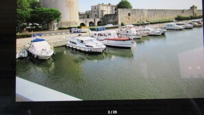 A harbor with boats docked, a large tower, and a historic building. - Le clos des oiseaux is a winery located in Aimargues. (Aimargues)