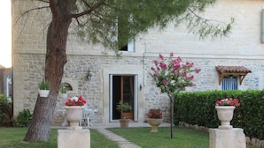 A stone building with a door, potted plants, and a pathway leading to the entrance. - Le clos des oiseaux is a winery located in Aimargues. (Aimargues)