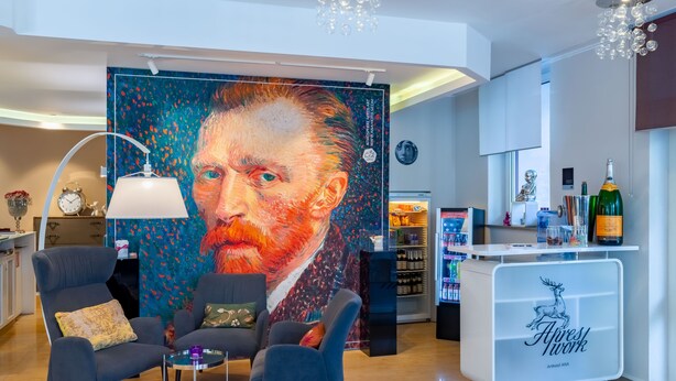 A modern lobby with a large abstract painting, comfortable seating, a reception desk, and a minibar. - Arthotel ANA Style (Augsburg)