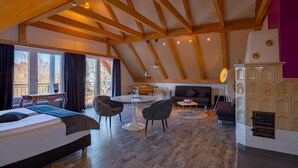 A spacious loft bedroom with a large bed, a dining table, and a sofa. - Arthotel ANA Style (Augsburg)