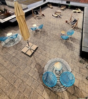 Una terraza en la azotea con mobiliario exterior, incluyendo mesas y sillas, y suelo estampado.