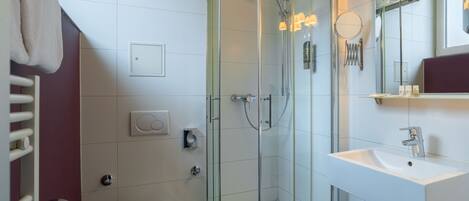 A modern bathroom with a glass-enclosed shower, a white sink, and a toilet.