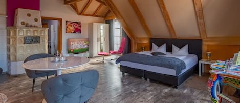 A cozy attic bedroom with a large bed, a dining table, and a kitchen area.