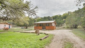 Una cabaña rústica con un sendero de tierra que la lleva a ella, rodeada de follaje y árboles.