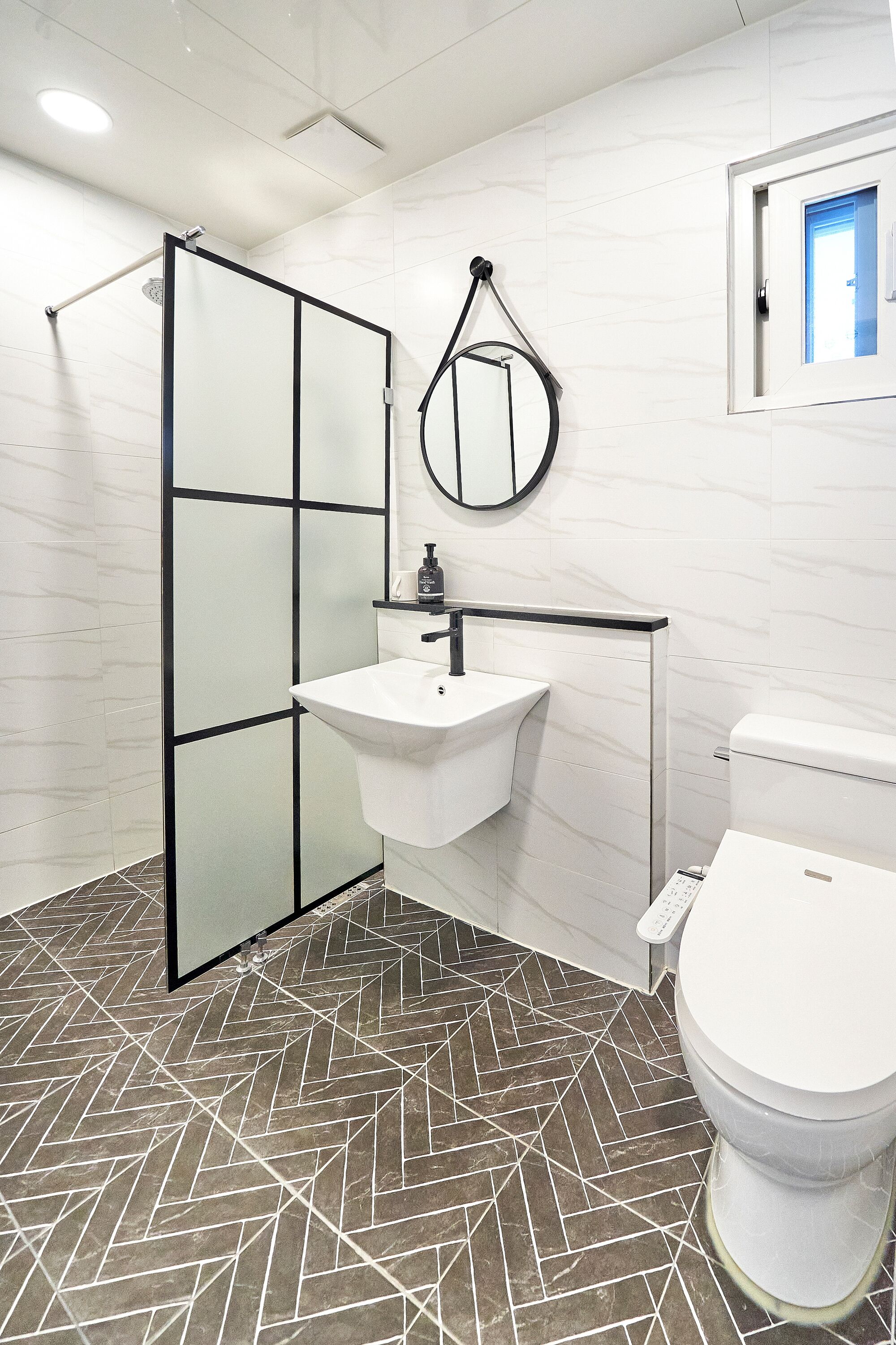 A bathroom with a shower, sink, toilet, and a mirror.