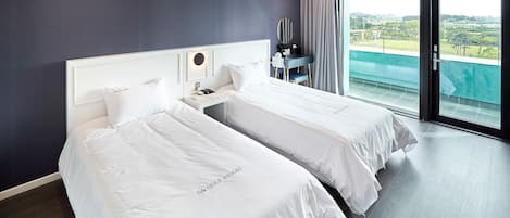 A hotel room with two beds, a desk, and a large window with a view.