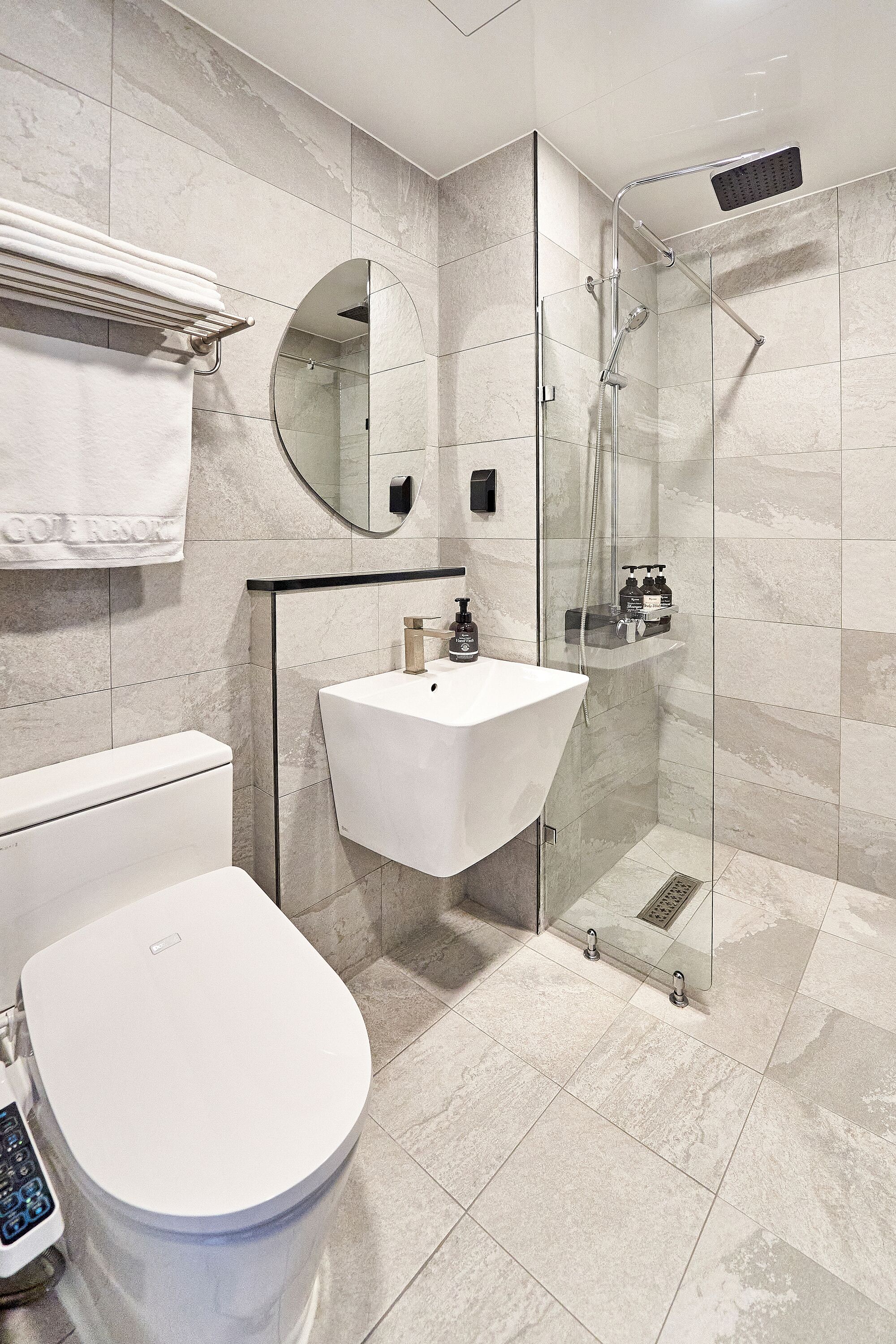 A modern bathroom with a toilet, sink, and glass-enclosed shower.