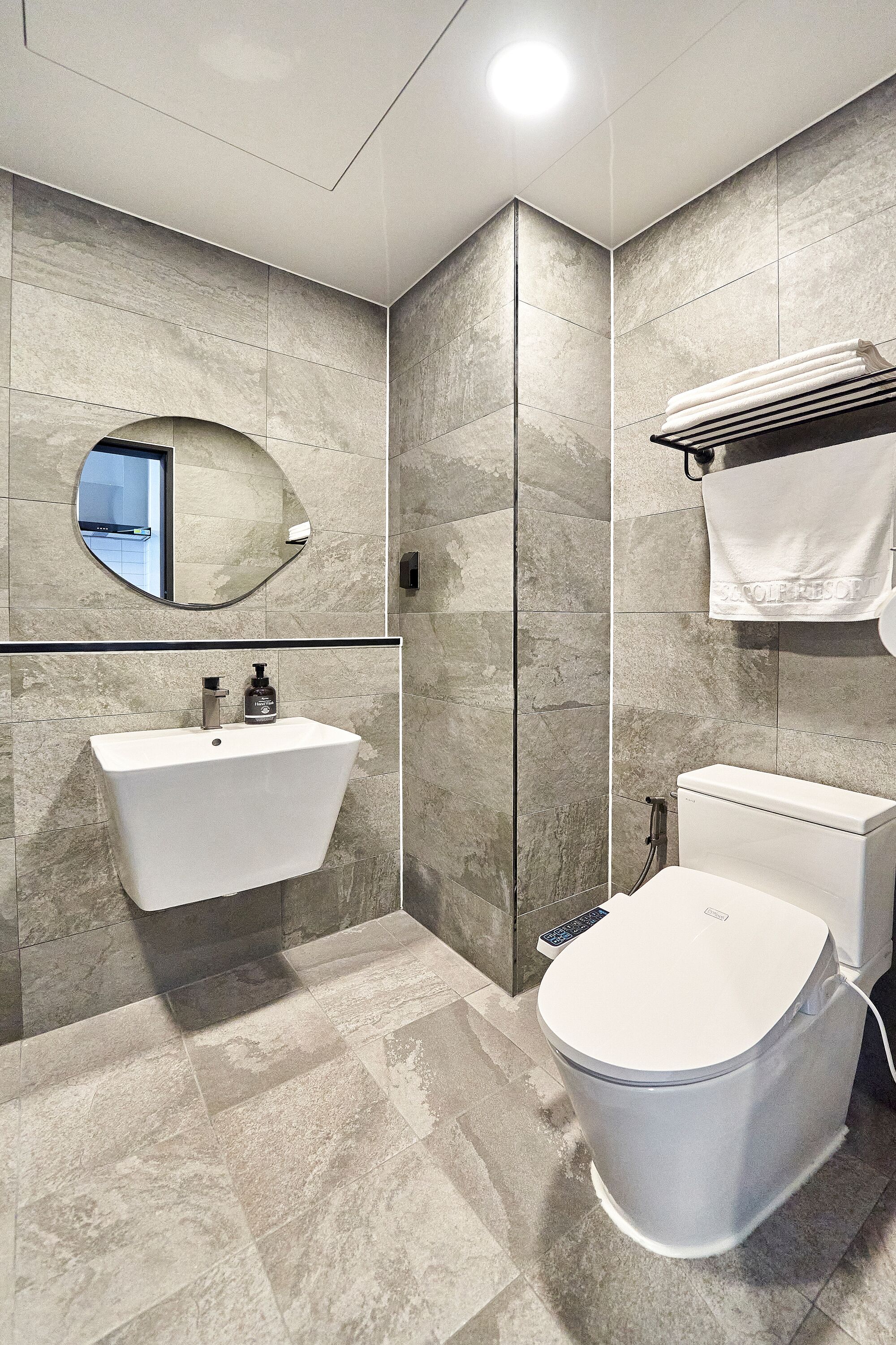 A modern bathroom with a built-in sink, a toilet, and a towel rack.