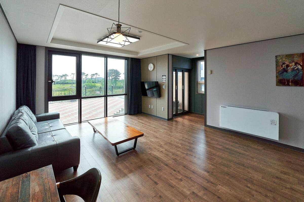 Una sala de estar moderna con un sofá, una mesa de centro de madera y un televisor montado en la pared.