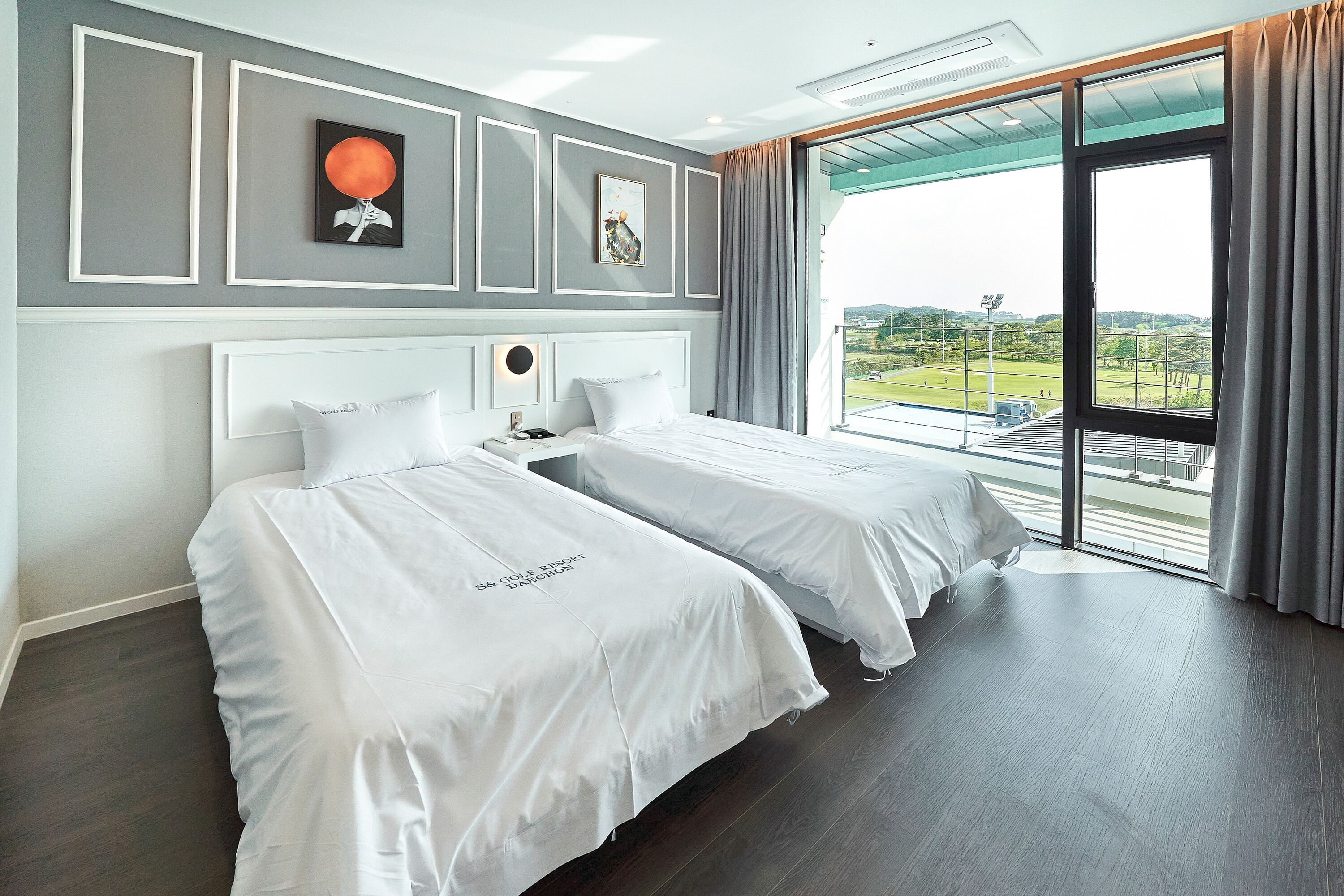 A hotel room with two beds, a large window with a view, and a modern design.