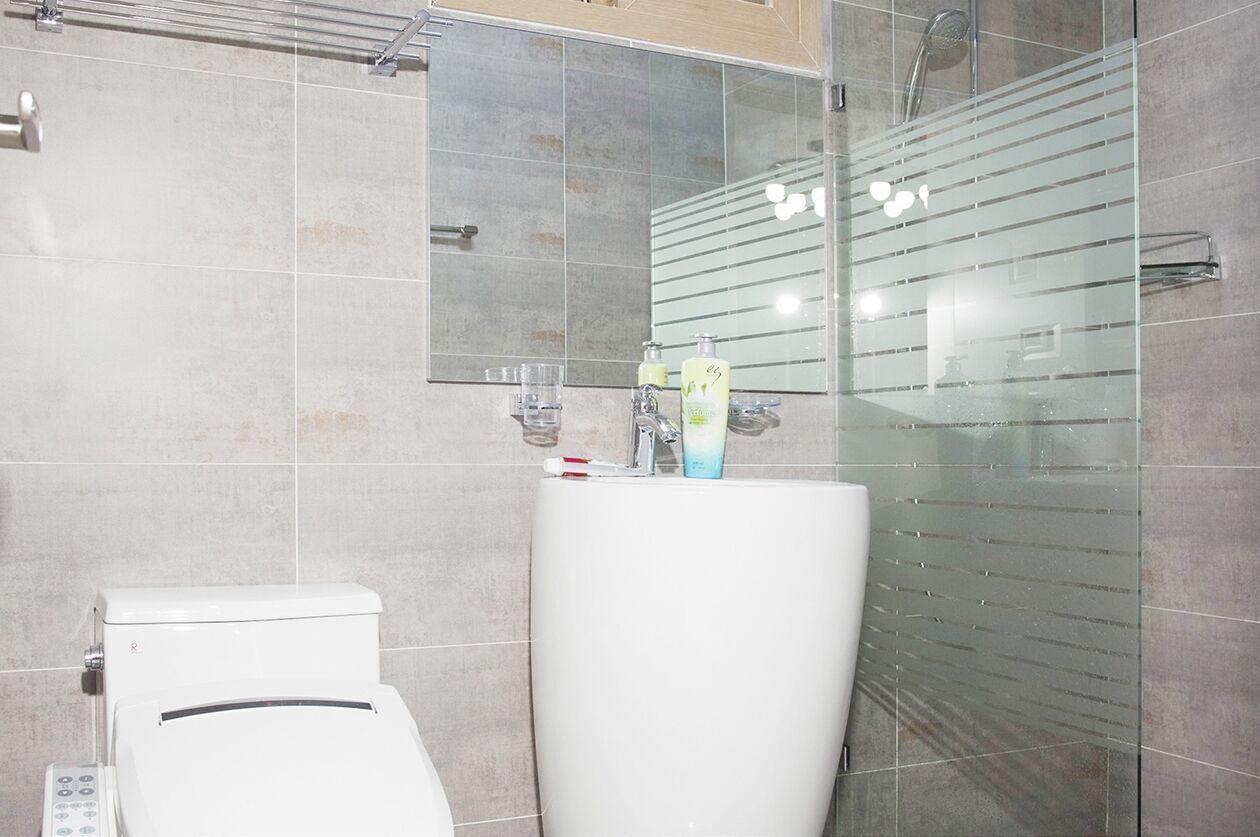 A bathroom with a toilet, a sink with a mirror, and a shower area.
