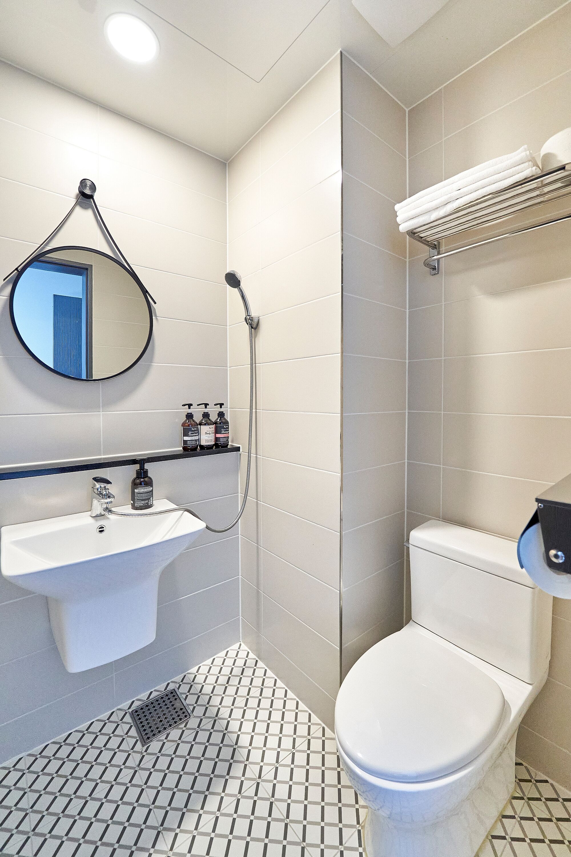 A bathroom with a white sink, a toilet, a shower, and a mirror.