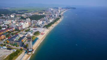 An aerial view of a coastal city with a beach, buildings, and a clear sky.