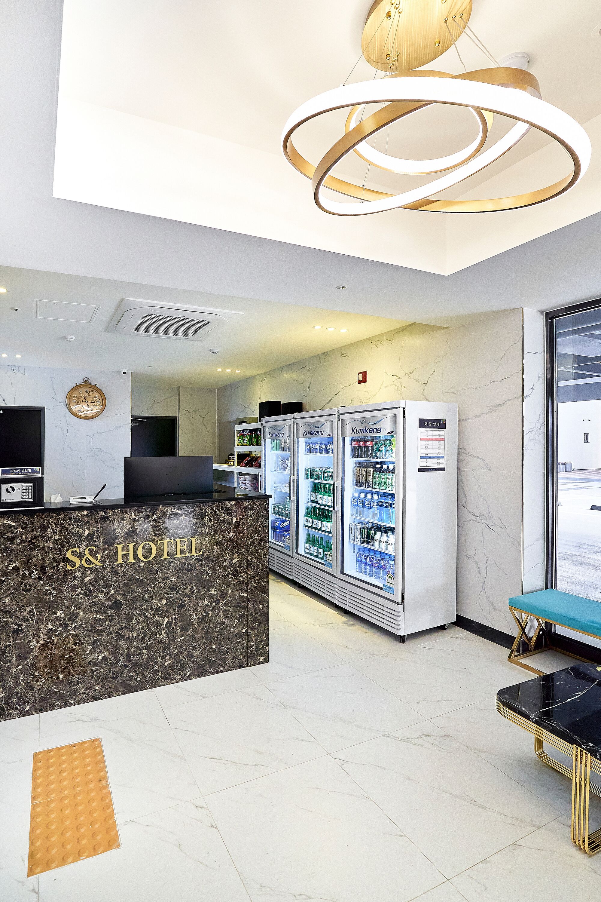 A hotel reception area with a marble counter, vending machines, and a modern chandelier.