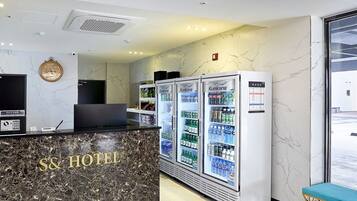 A hotel reception area with a marble counter, vending machines, and a modern chandelier.