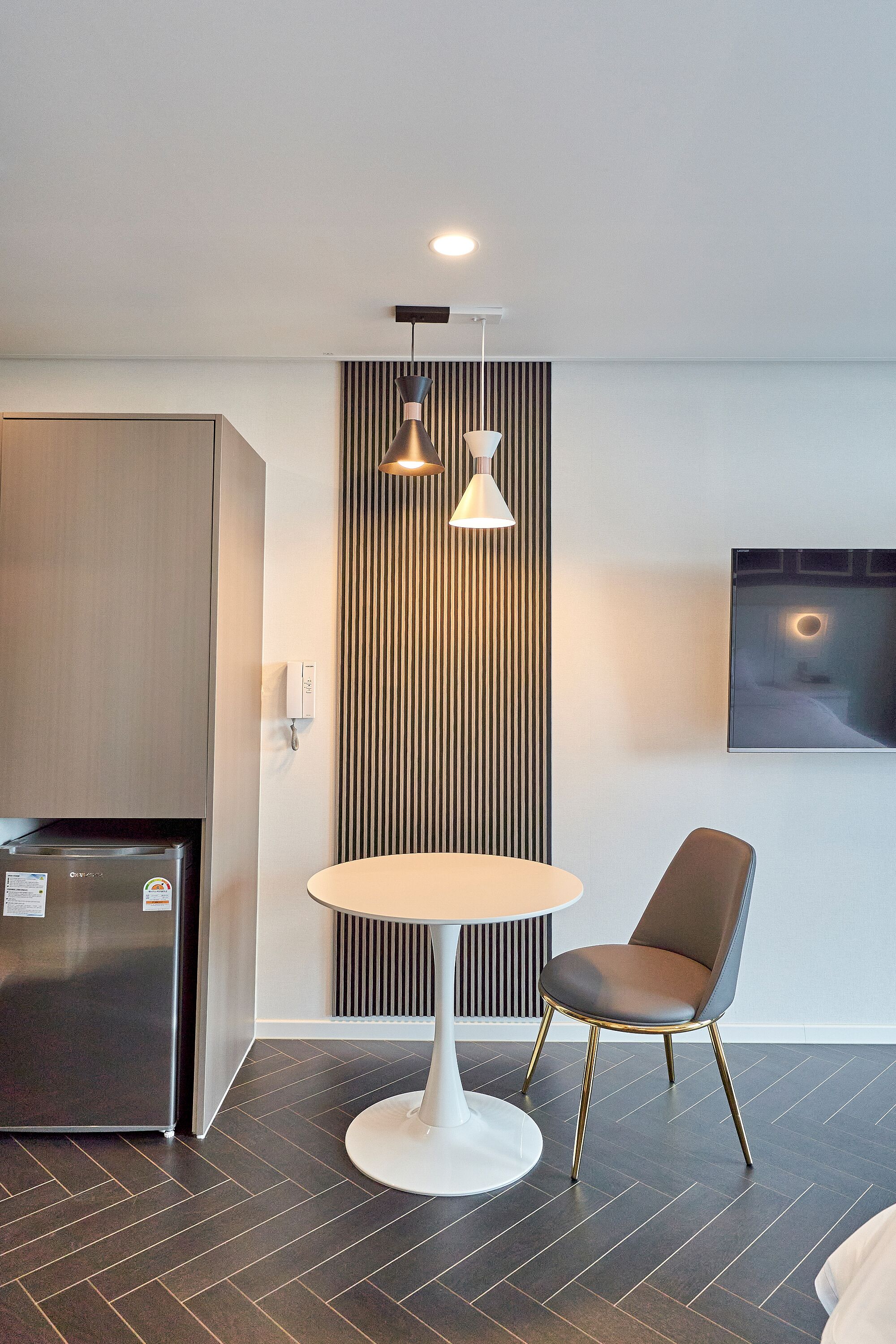 Una cocina moderna con refrigerador incorporado, una mesa de comedor redonda y una sola silla.