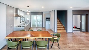 Eine moderne Küche mit Holztisch und grünen Stühlen, einer Mikrowelle und einem Kühlschrank.