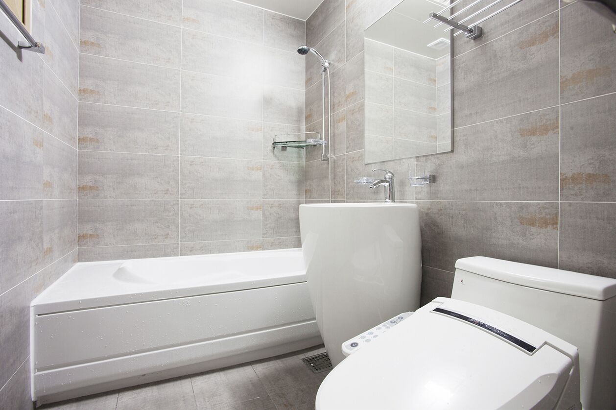 Ein modernes Badezimmer mit Badewanne, Toilette und einer Glasablage.