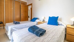 Ett hotellrum med två sängar, en garderob, ett nattduksbord med en lampa och en luftkonditioneringsanläggning.