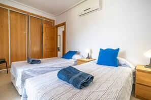 A hotel room with two beds, a wardrobe, a bedside table with a lamp, and an air conditioning unit. - A well located apartment with pool views - CO212LT (Torre-Pacheco)