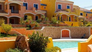 Um hotel com vários edifícios coloridos, piscina e jardins bem cuidados.