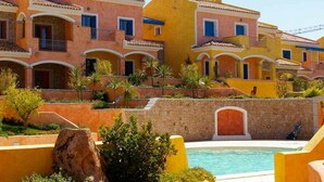 Un hotel con diversi balconi, piscina e giardino curato.