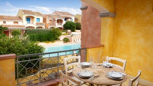 Un balcon avec une table dressée pour le dîner, donnant sur une piscine et une plage.