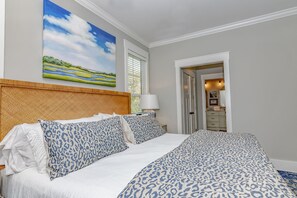 Een hotelkamer met een groot bed, een landschapsschilderij en uitzicht op de gang.