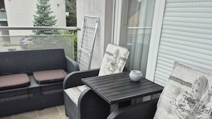 A balcony with wicker furniture, including two sofas and a small table, and a glass door. - Apartment Josip (Zagreb)