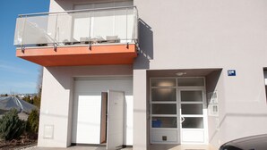 A building with a white facade, a balcony with a metal railing, and a garage door. - Apartment Josip (Zagreb)
