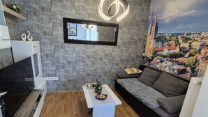 A modern living room with a wooden floor, a grey sofa, a white coffee table, and a cityscape mural on the wall. - Apartment Josip (Zagreb)