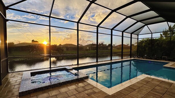 A covered swimming pool with a view of the sunset and surrounding landscape. - Private Pool: Canalfront Home in Cape Coral (Cape Coral)