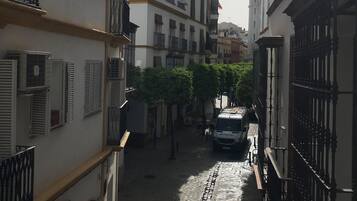 A narrow cobblestone street flanked by buildings with balconies and air conditioning units.