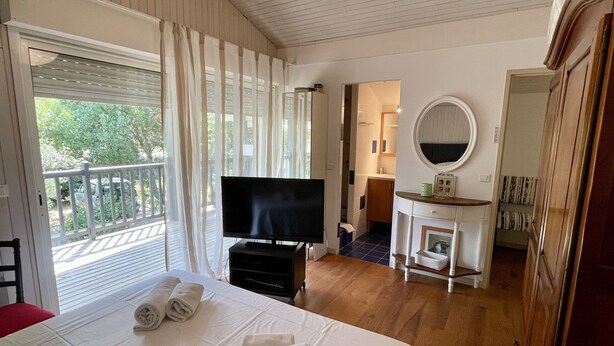 A hotel room with a bed, a TV, a bathroom, and a balcony. - Very attractive holiday home with pool, wonderful terrace and garden (Le Canon)