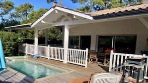 A wooden deck with a pool, outdoor furniture, and a covered patio area. - Very attractive holiday home with pool, wonderful terrace and garden (Le Canon)