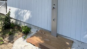 A white building with a metal door and a wooden deck. - Very attractive holiday home with pool, wonderful terrace and garden (Le Canon)