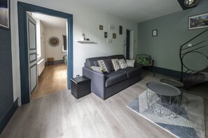 A modern living room with a grey sofa, a coffee table, and a small side table. There is a staircase leading to an upper level. - i-love-colmar - Le 8 de Coeur - Free garage (COLMAR)