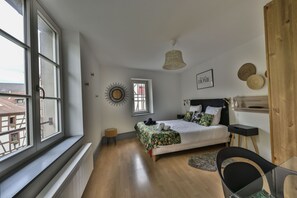 Ein Schlafzimmer mit Bett, Schreibtisch und Stuhl. Ein Fenster bietet Blick auf Gebäude.