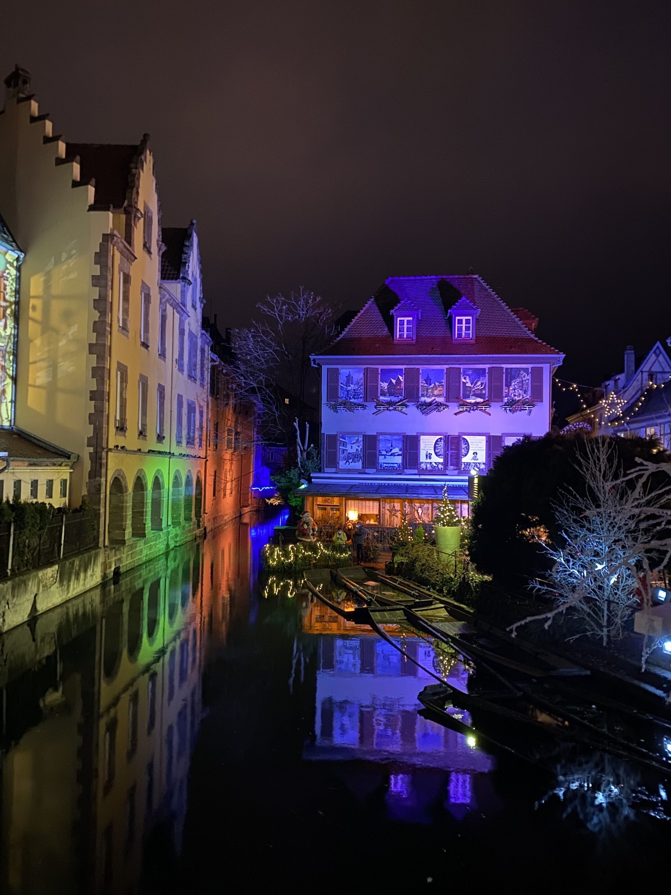 Un edificio histórico con un canal reflectante en primer plano, que presenta un estilo arquitectónico tradicional europeo.